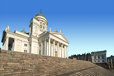 Vit byggnad med kupol och pelare, sett från stentrappa under klarblå himmel.