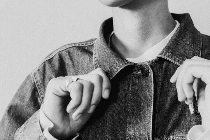 Person i jeansjacka knäpper knappen. Svartvitt foto.