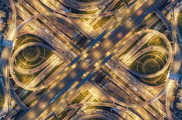 Flygbild av upplyst trafikled med komplexa vägbanor i ett mönster.