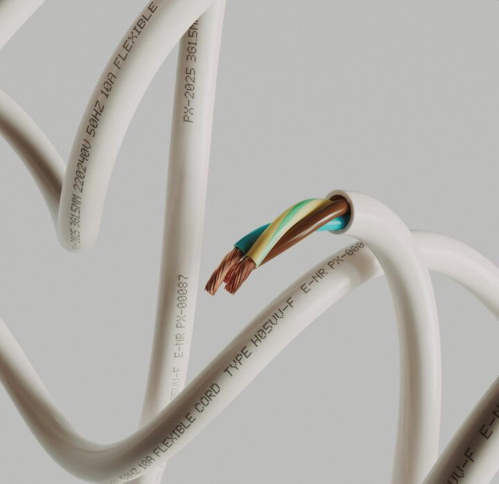 Vita elektriska kablar med synliga kopparledare på grå bakgrund.