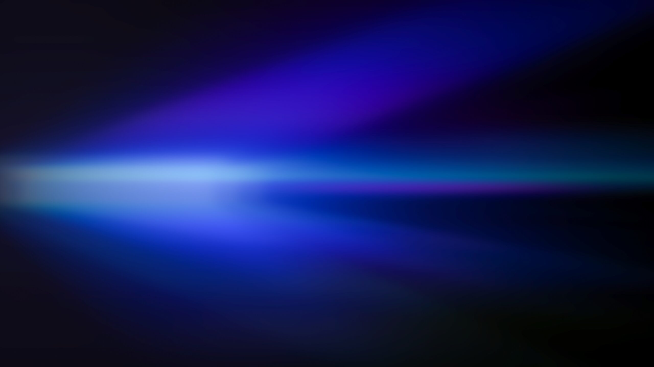 Abstract blurred blue and purple light streaks on a dark background.