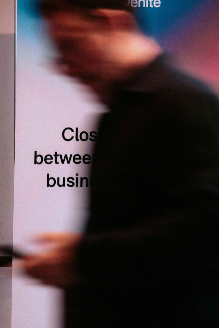 Blurry person walking past a sign with partially visible text reading "Close between busin".